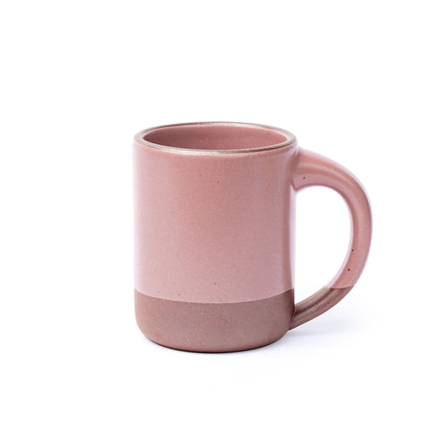 A big sized ceramic mug with handle in a soft pink color featuring iron speckles and unglazed rim and bottom base.