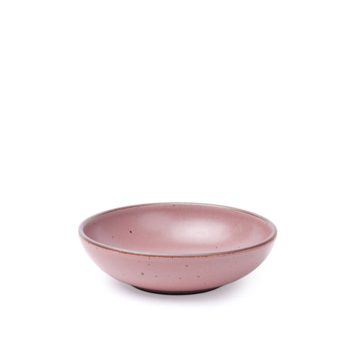 A dinner-sized shallow ceramic bowl in a pink color featuring iron speckles and an unglazed rim