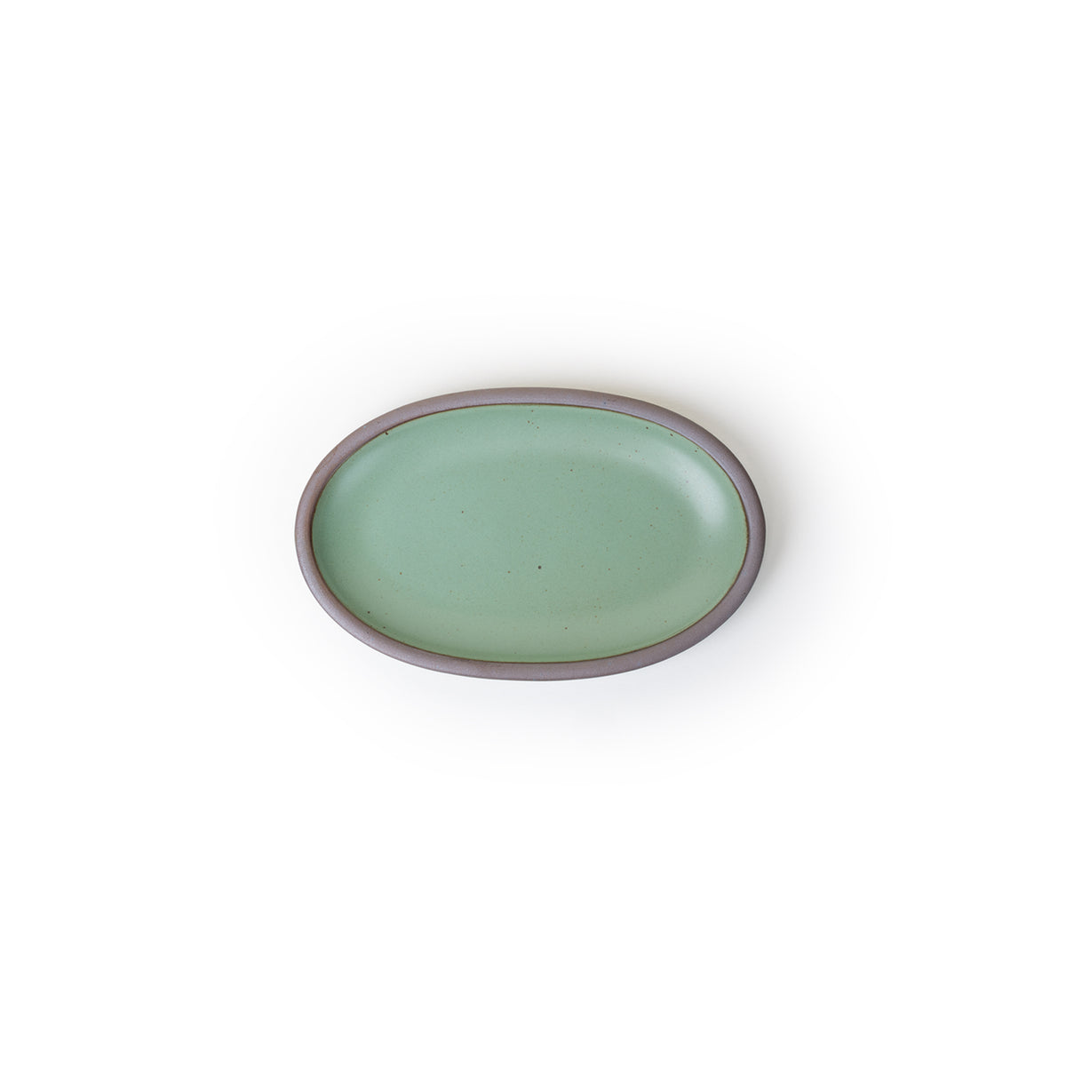 A small oval ceramic platter in a green color featuring iron speckles and an unglazed rim