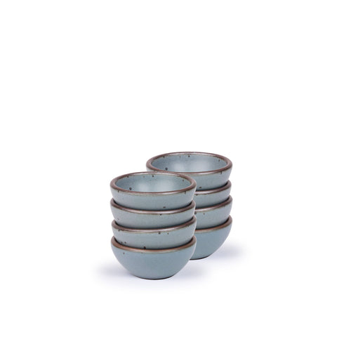 A stack of 8 tiny rounded ceramic bowls in a blue-grey color featuring iron speckles and an unglazed rim