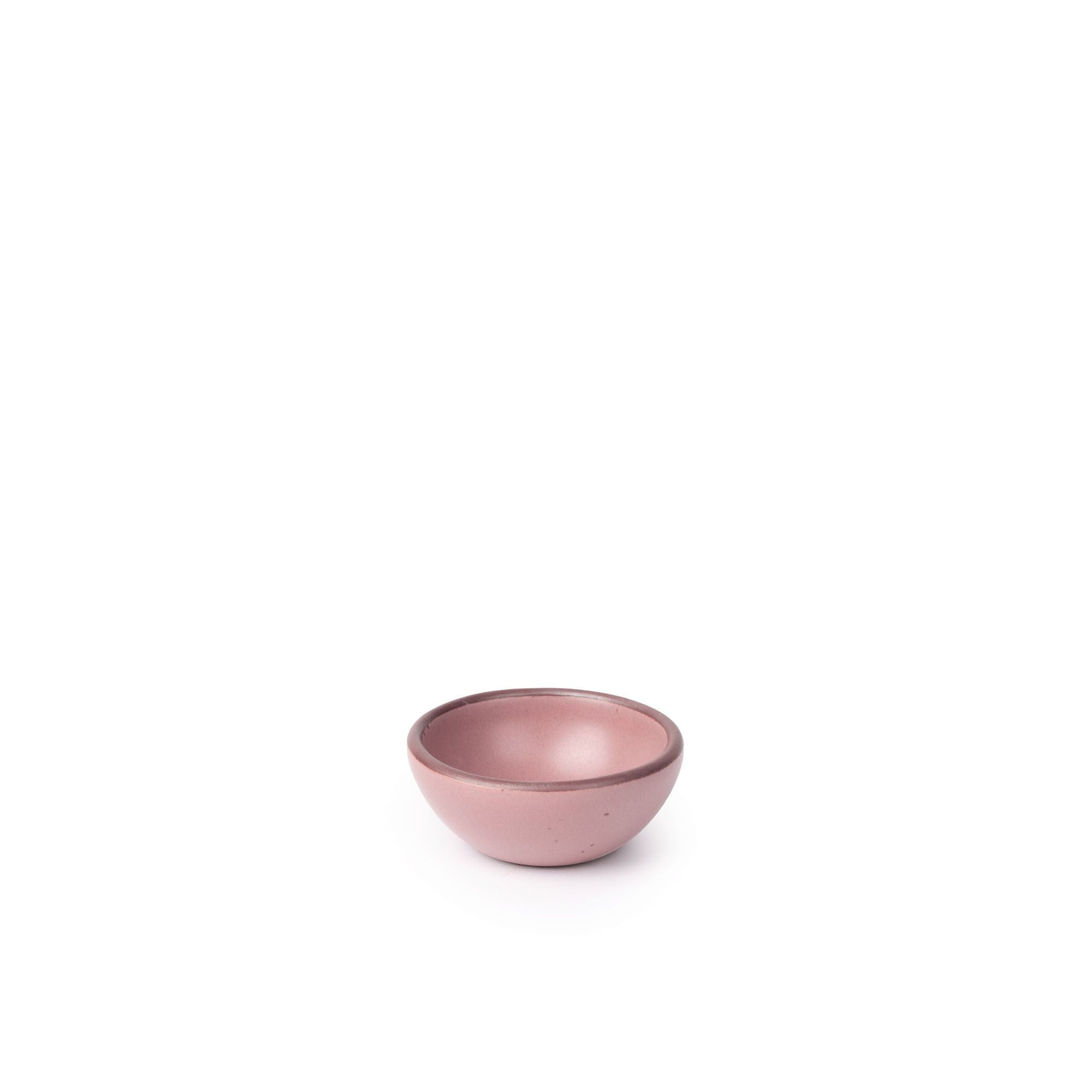 A tiny rounded ceramic bowl in a dusty mauve pink color featuring iron speckles and an unglazed rim