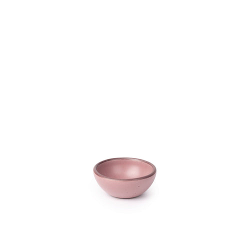 A tiny rounded ceramic bowl in a dusty mauve pink color featuring iron speckles and an unglazed rim