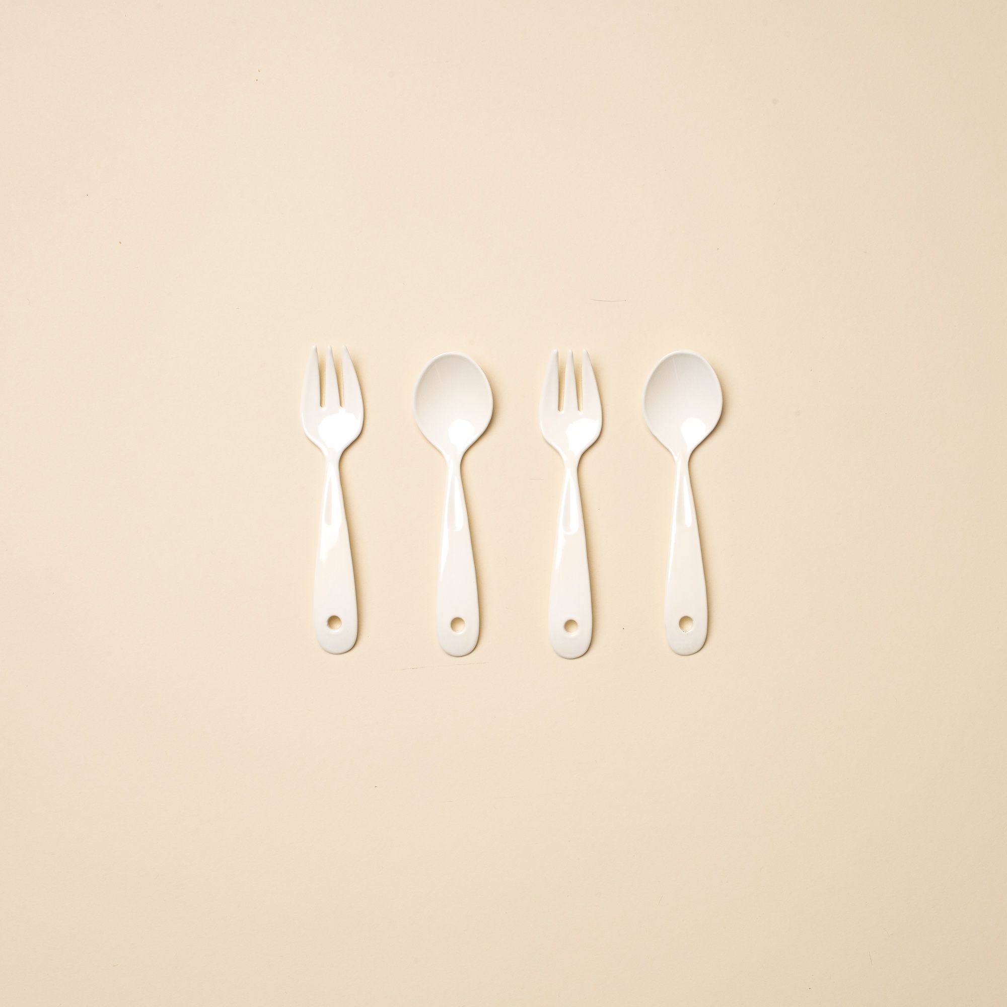 4 white enamel mini forks and spoons in a row.