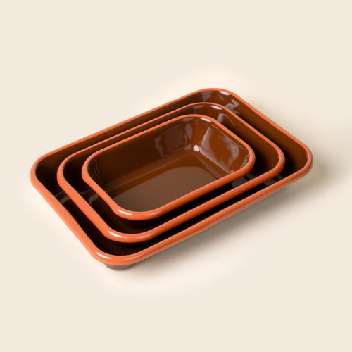 A nesting trio of small, medium, and large rectangular baking dishes in a glossy red-brown color with an orange rim.
