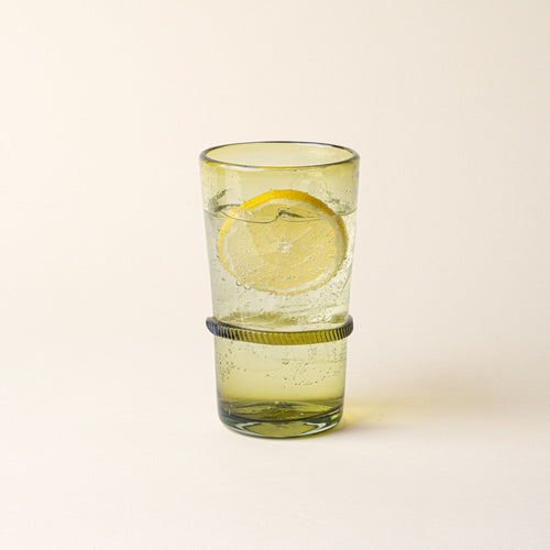 An olive tall recycled glass tumblers with a ridged band detail, filled with water and a lemon slice.