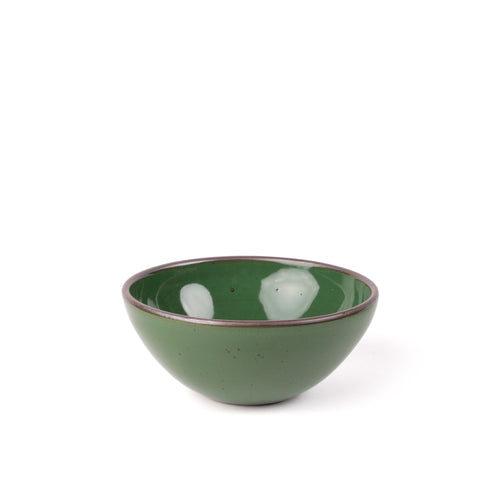 A medium rounded ceramic bowl in a glossy emerald green color featuring iron speckles and an unglazed rim