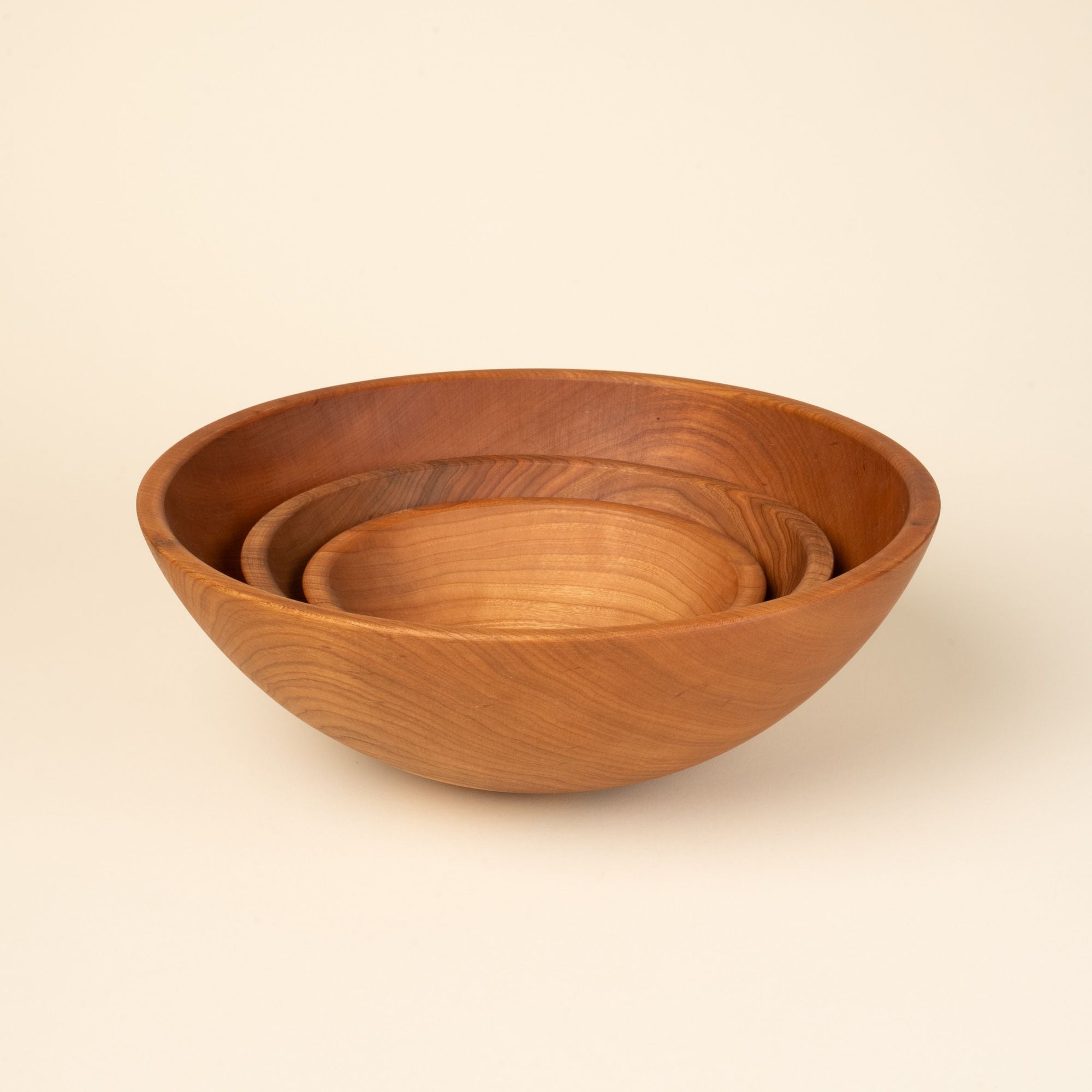 3 round cherry wood bowls nesting together in small, medium, and large sizes.