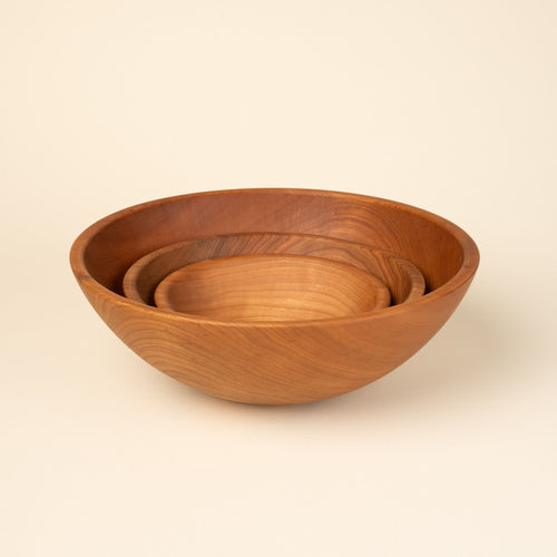 3 round cherry wood bowls nesting together in small, medium, and large sizes.