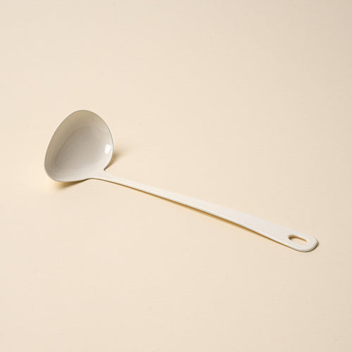 A white enamel sauce ladle with a hole at the end of the handle for hanging