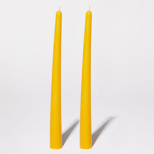 two yellow tapered beeswax candles