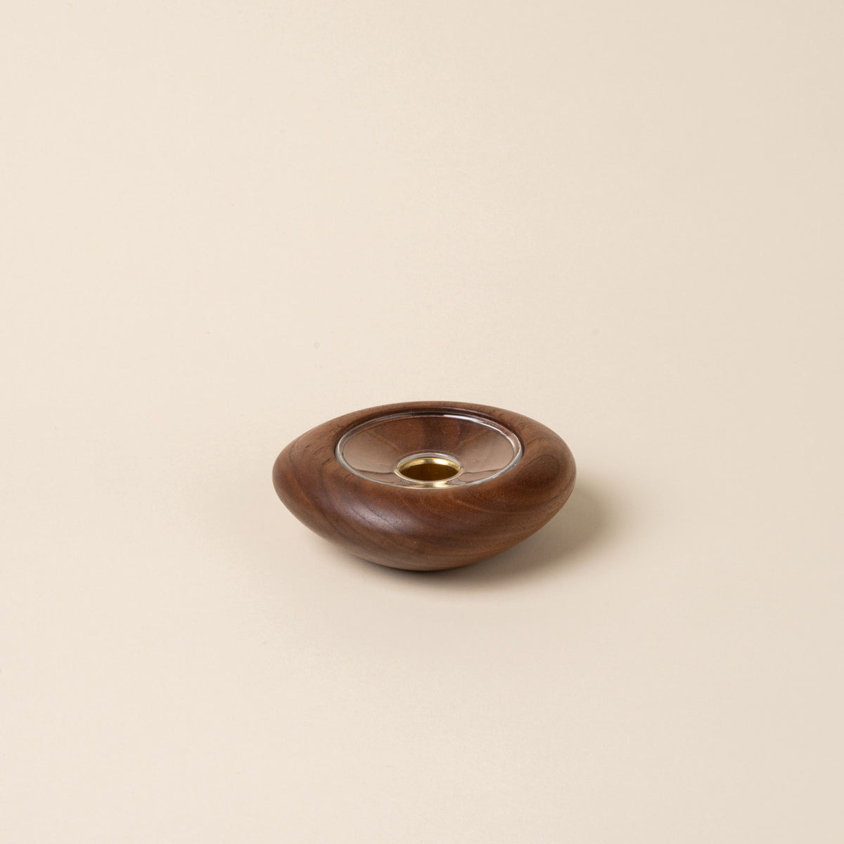 Small round walnut wood candle holder with visible grain and a glass insert in the center, displayed against a neutral background.