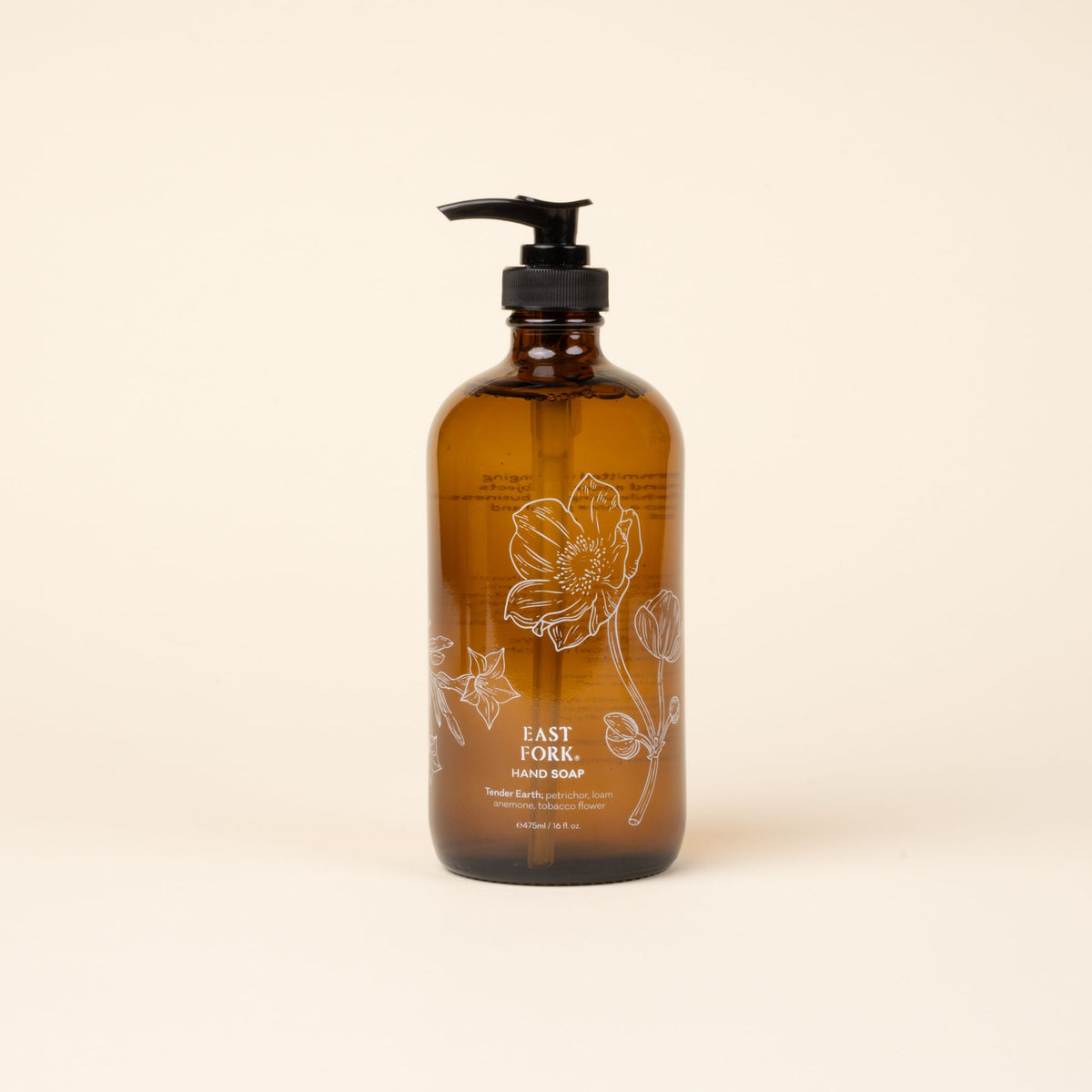 Amber glass pump bottle of East Fork hand soap with floral illustration, centered against a light neutral background.