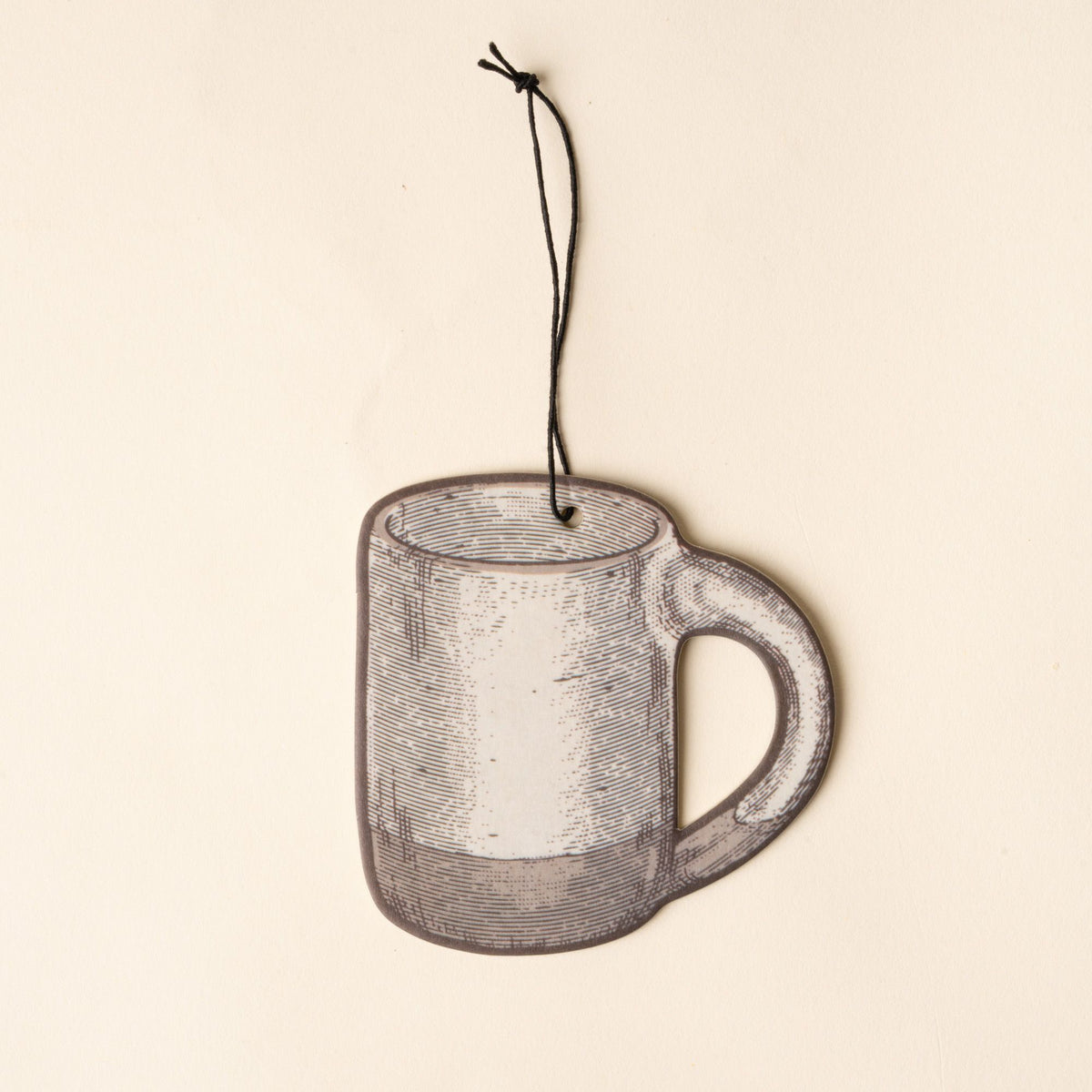 Illustrated mug-shaped air freshener in a cool white color with a black hanging string against a light cream background.