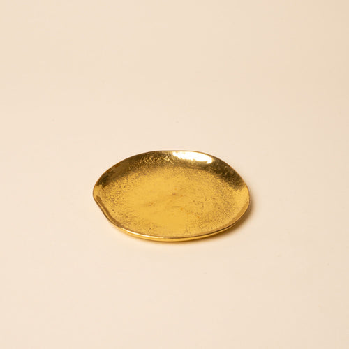 Small round gold dish with a hammered texture, sitting empty on a neutral background.