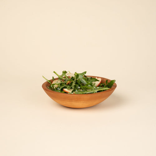 A salad in a small cherry wood bowl