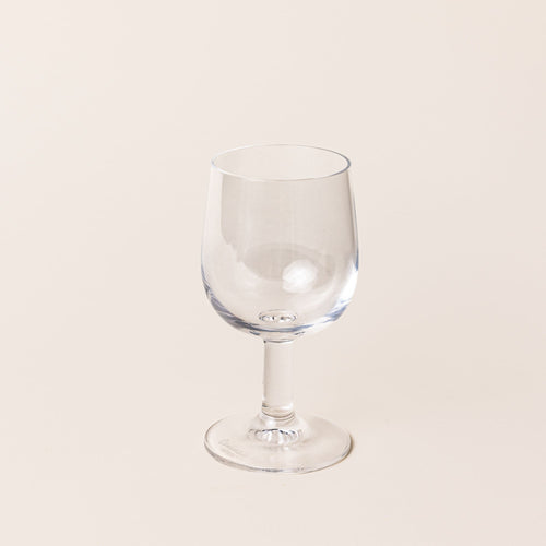 A clear wine glass with a short stem and wide cup.