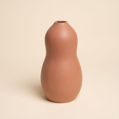 Large light terracotta ceramic vase with a curvy shape and subtle speckles, set against a soft beige background.