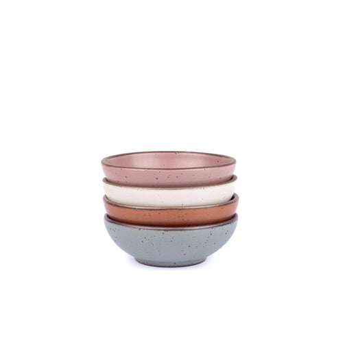 A stack of 4 small shallow ceramic bowls in a cool terracotta, warm off-white, blue-grey, dusty mauve pink colors featuring iron speckles and an unglazed rim