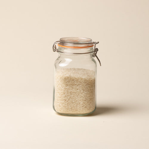 A medium storage glass square jar filled with rice, topped with a lid with a rubber seal and steel clip closure.