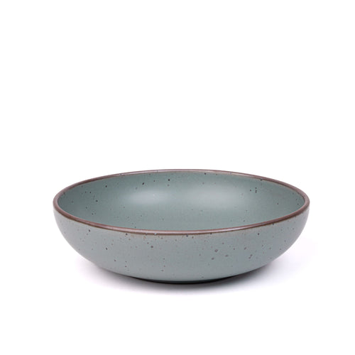 A large shallow serving ceramic bowl in a blue-grey color featuring iron speckles and an unglazed rim.