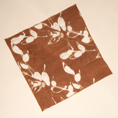 A square brown napkin with white botanical print on a neutral background.