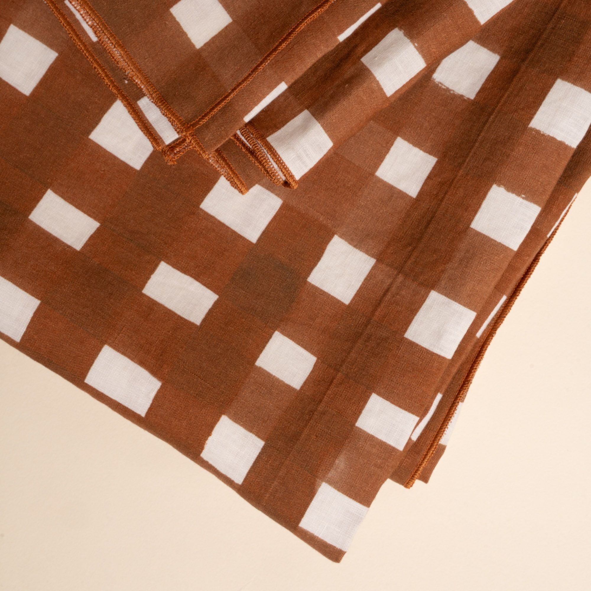 A close up of a folded table runner featuring a brown and white crosshatch pattern