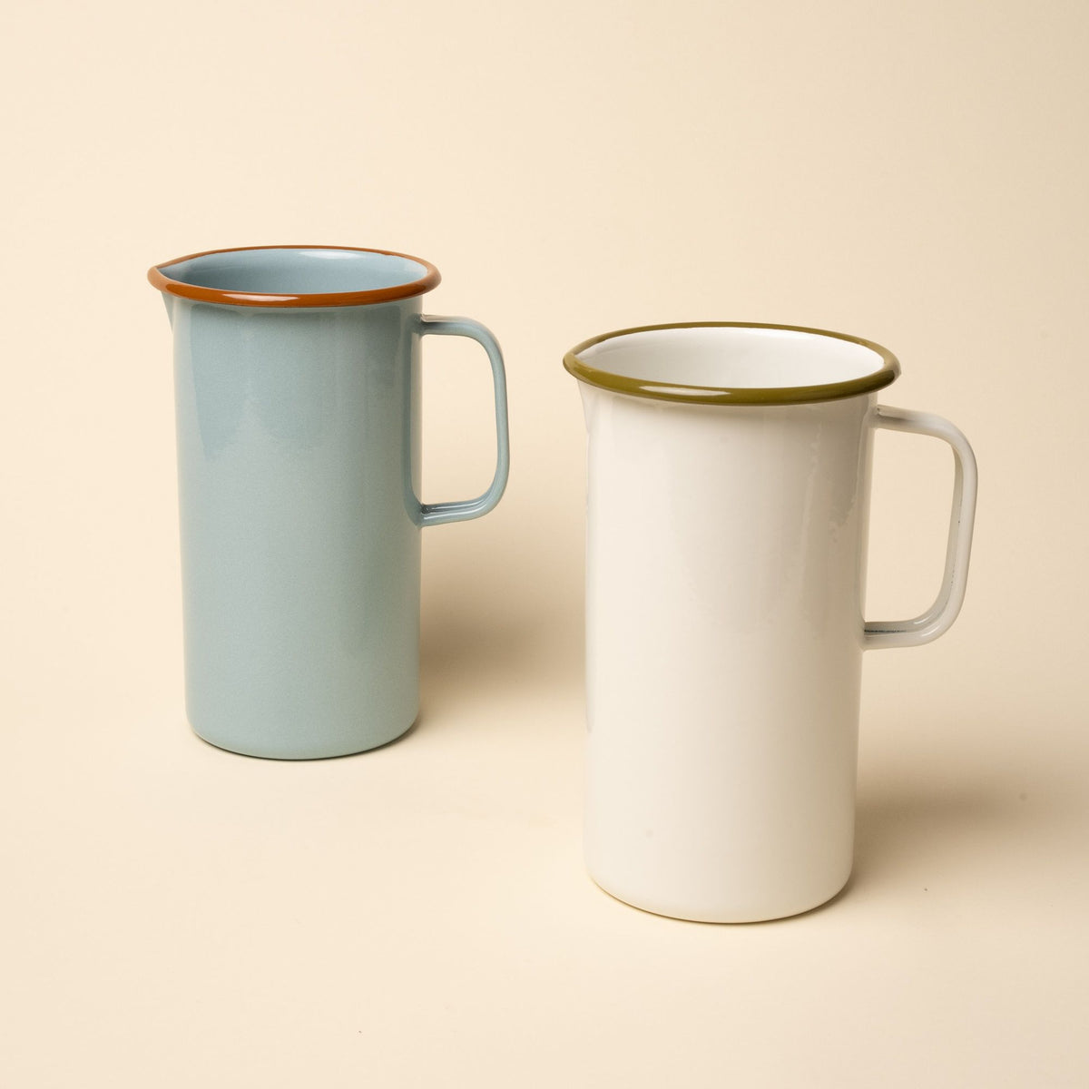2 enamel pitchers, the left is robin egg's blue with a warm brown rim. The right is a white color with a olive green rim.