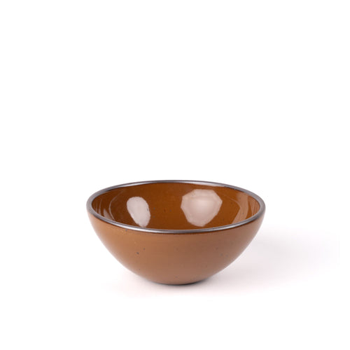 A medium rounded ceramic bowl in a glossy caramel brown color featuring iron speckles and an unglazed rim