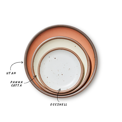 A stack of 3 plates in Dinner, Side, and Cake sizes in a warm peach, warm off-white, and white colors.