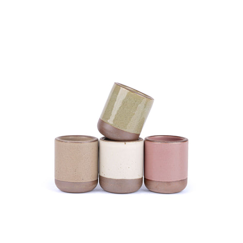 A set of 4 small, short ceramic mug cups in a warm pale brown, warm off-white, reflective dappled grey-green, and dusty mauve pink colors featuring iron speckles and unglazed rim