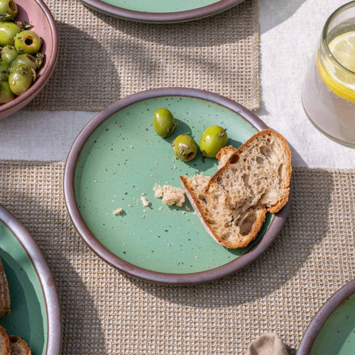 A small ceramic plates with flat surfaces and raised edges in a viridian green glaze with a matte finish.