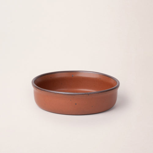 Wide shallow ceramic ramekin in a cool terracotta color with an unglazed rim