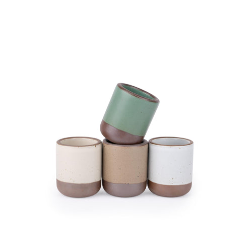 Four handleless ceramic cups for small pours in a viridian green, warm brown, warm white and cool white glazes.