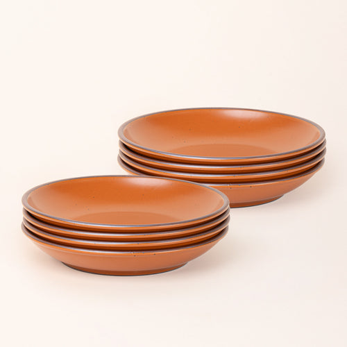 2 stacks of 4 large ceramic plates with a curved bowl edge in an earthy orange color featuring iron speckles and an unglazed rim.