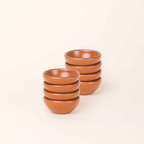 2 stacks of 4 tiny rounded ceramic bowls in an earthy orange color featuring iron speckles and an unglazed rim