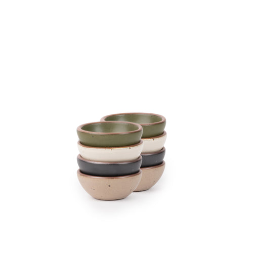 8 tiny rounded ceramic bowls in an olive green, graphite black, off-white, and warm pale brown colors featuring iron speckles and an unglazed rim