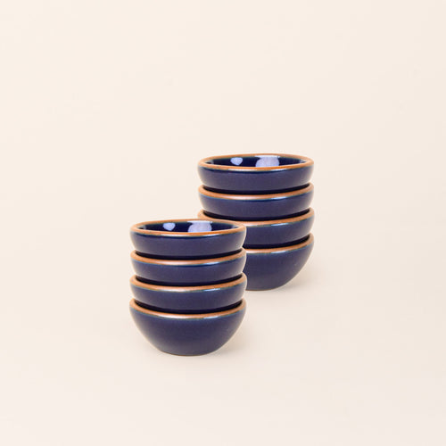 2 stacks of 4 tiny rounded ceramic bowls in a glossy dark blue color featuring iron speckles and an unglazed rim