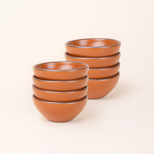 2 stacks of 4 small dessert sized rounded ceramic bowls in an earthy orange color featuring iron speckles and an unglazed rim