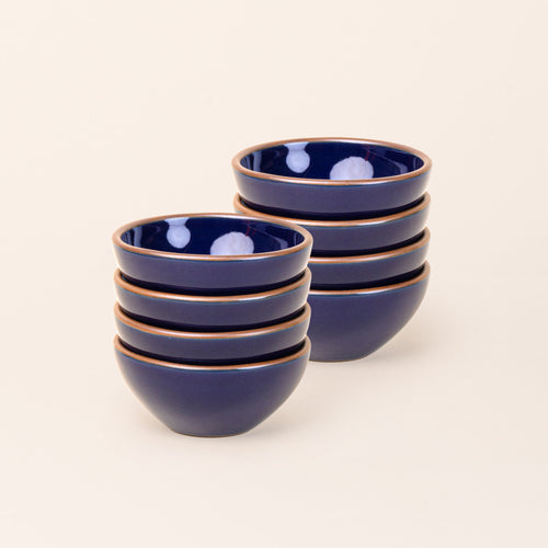 2 stacks of 4 small dessert sized rounded ceramic bowls in a glossy dark blue color featuring iron speckles and an unglazed rim