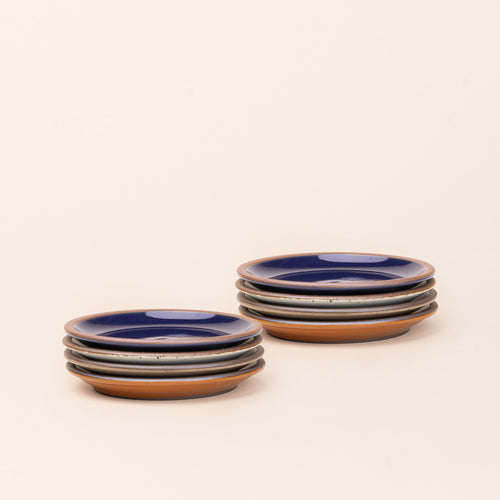 8 dessert sized ceramic plates in a glossy dark blue, earthy orange, warm pale brown and white colors featuring iron speckles and an unglazed rim