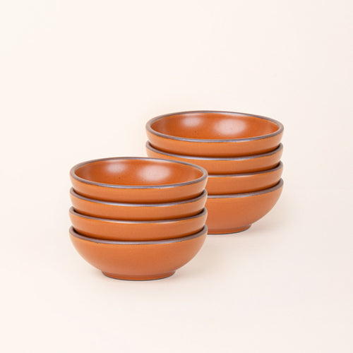 2 stacks of 4 small shallow ceramic bowls in an earthy orange color featuring iron speckles and an unglazed rim