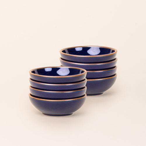 2 stacks of 4 small shallow ceramic bowls in a glossy dark blue color featuring iron speckles and an unglazed rim