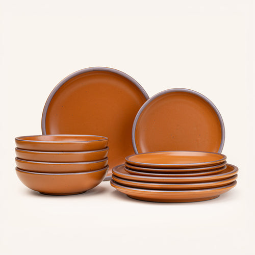 A set of stoneware dinnerware including four dinner plates, four side plates, and four bowls in an earthy orange color with iron speckles.