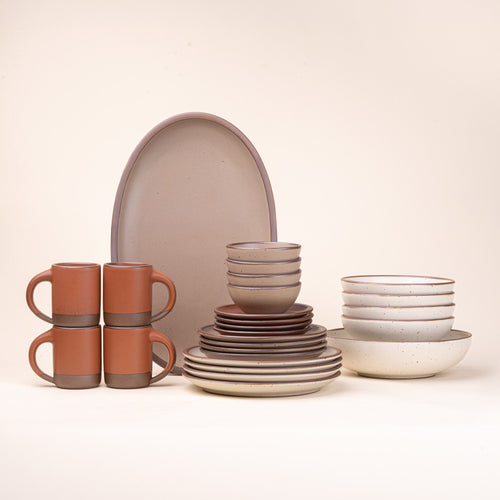 A 26-piece tablesetting with four mugs, four cake plates, four side plates, four dinner plates, 4 shallow bowls, 4 ice cream bowls, a large shallow bowl and an oval platter in a warm off-white, terracotta, and pale brown colors.