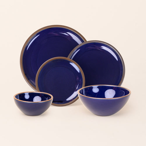 An ice cream bowl, soup bowl, cake plate, side plate and dinner plate paired together in a glossy dark blue color featuring iron speckles