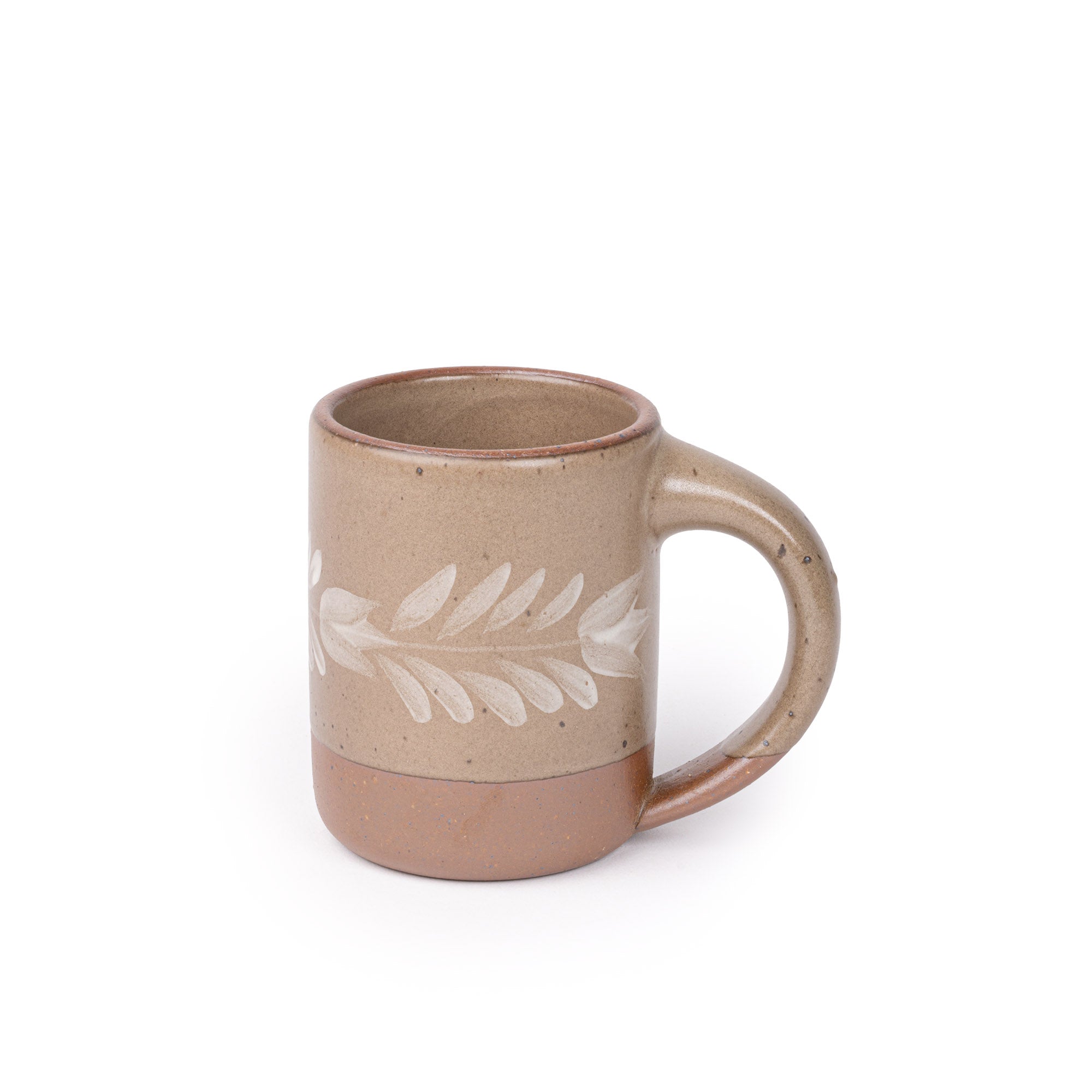 Pale warm brown ceramic mug with a hand-painted white leaf motif and exposed clay base on a plain white background.