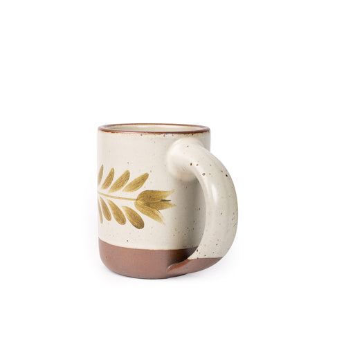Side profile of a Warm off-white ceramic mug with a hand-painted olive green leaf motif and exposed clay base on a plain white background.