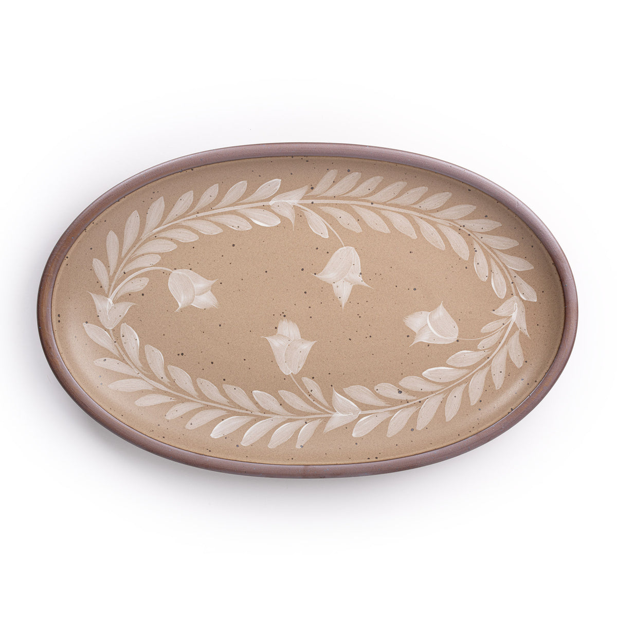 Oval ceramic platter with a hand-painted white leaf and flower border on a warm pale brown background with an exposed clay rim.