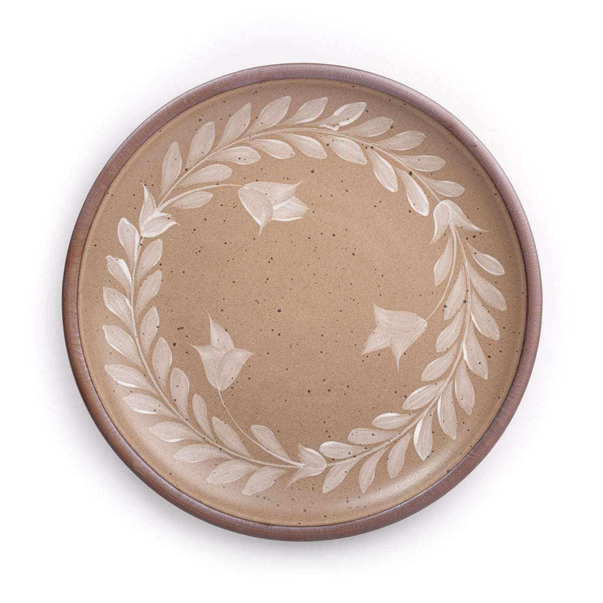 Large round ceramic platter with a hand-painted white leaf wreath and floral design on a warm pale brown background with an exposed clay rim.