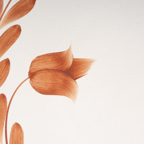 Closeup of a large round ceramic platter with a hand-painted cool terracotta leaf wreath and floral design on a cream background with an exposed clay rim.